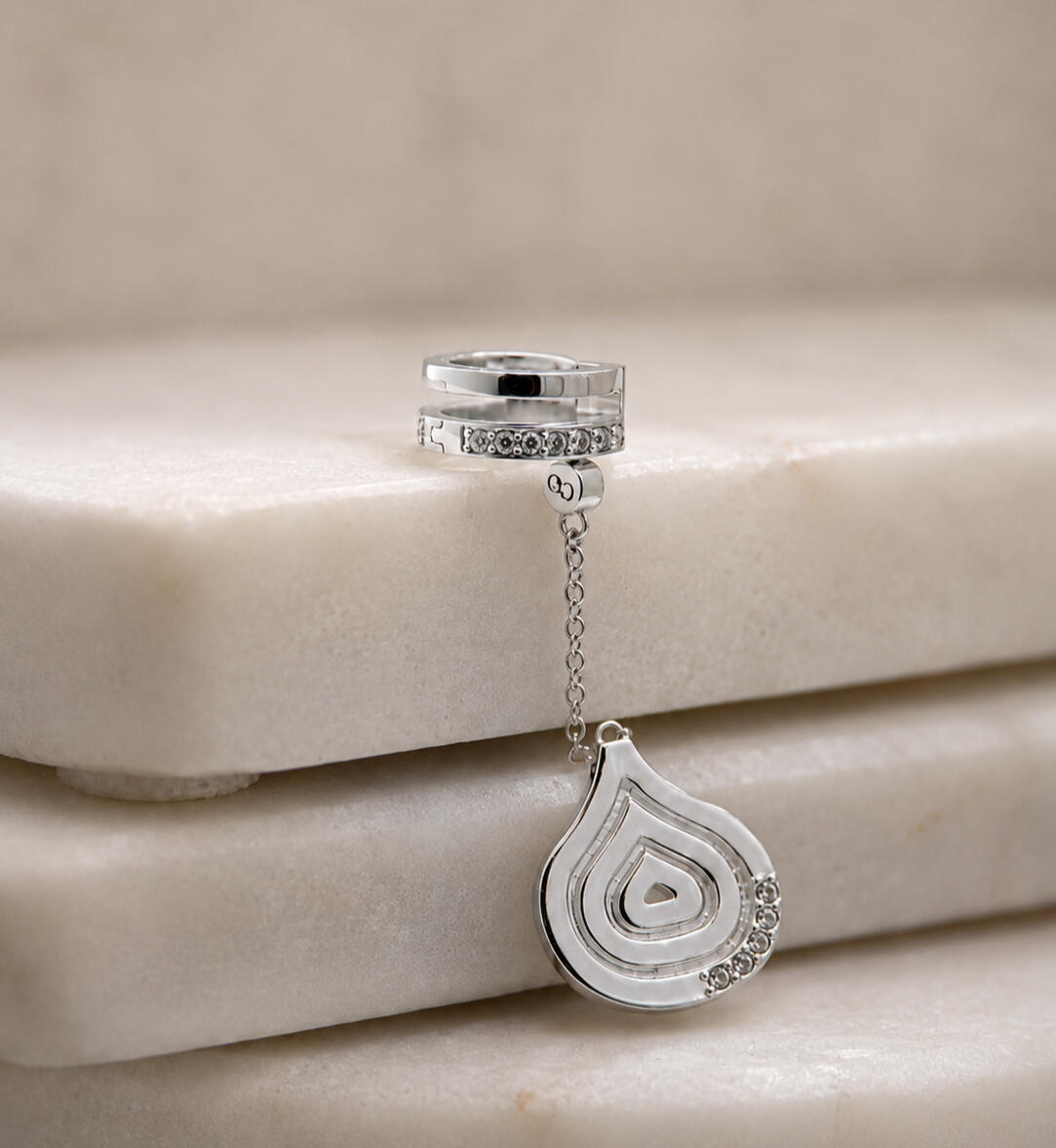 a silver hair cuff and pendant on white background