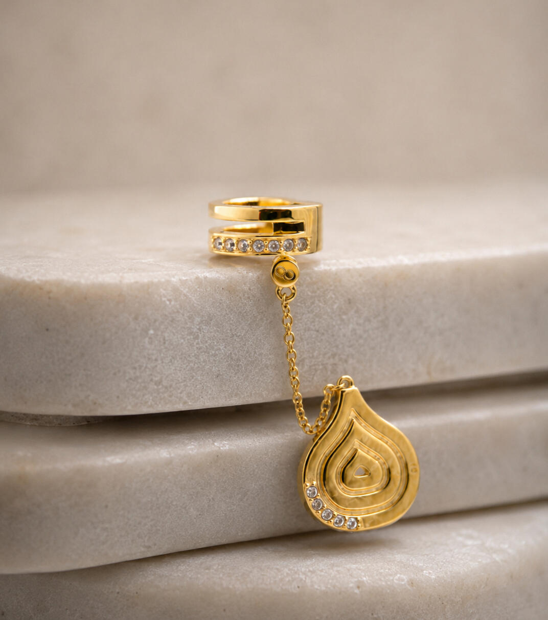 a gold hair cuff and pendant on white background